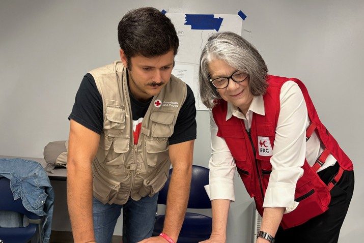 Kate Forbes standing with a young man wearing a vest and Red Cross t-shirt.