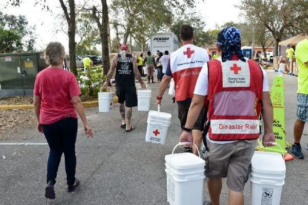 Red Cross volunteers carrying buckets in each hand