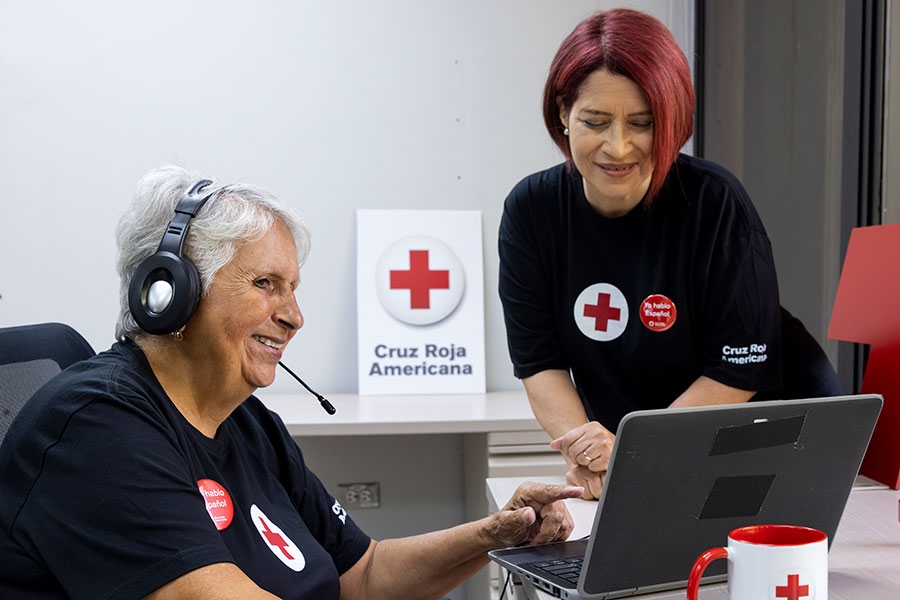 Dos voluntarias en un escritorio mirando una computadora portátil.