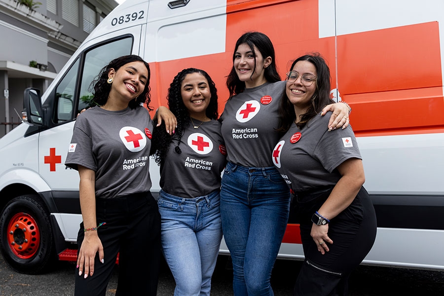 Cuatro voluntarias de pie delante de una camioneta de la Cruz Roja.