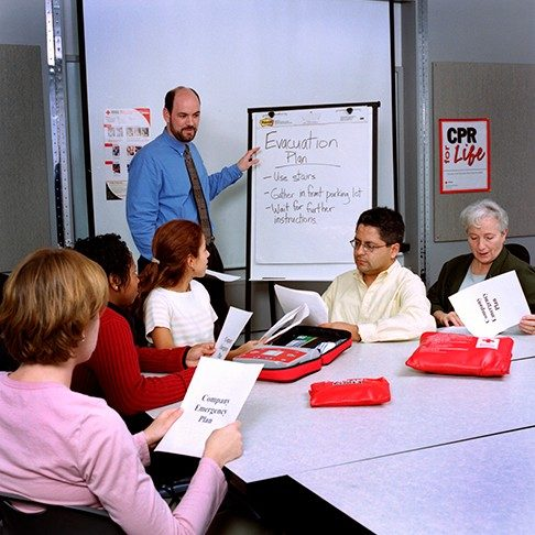 man teaching evacuation plan to group of people