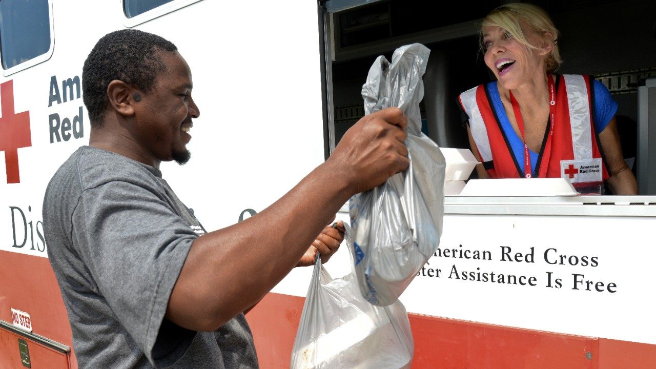 A Red Cross volunteer giving out a box meal.