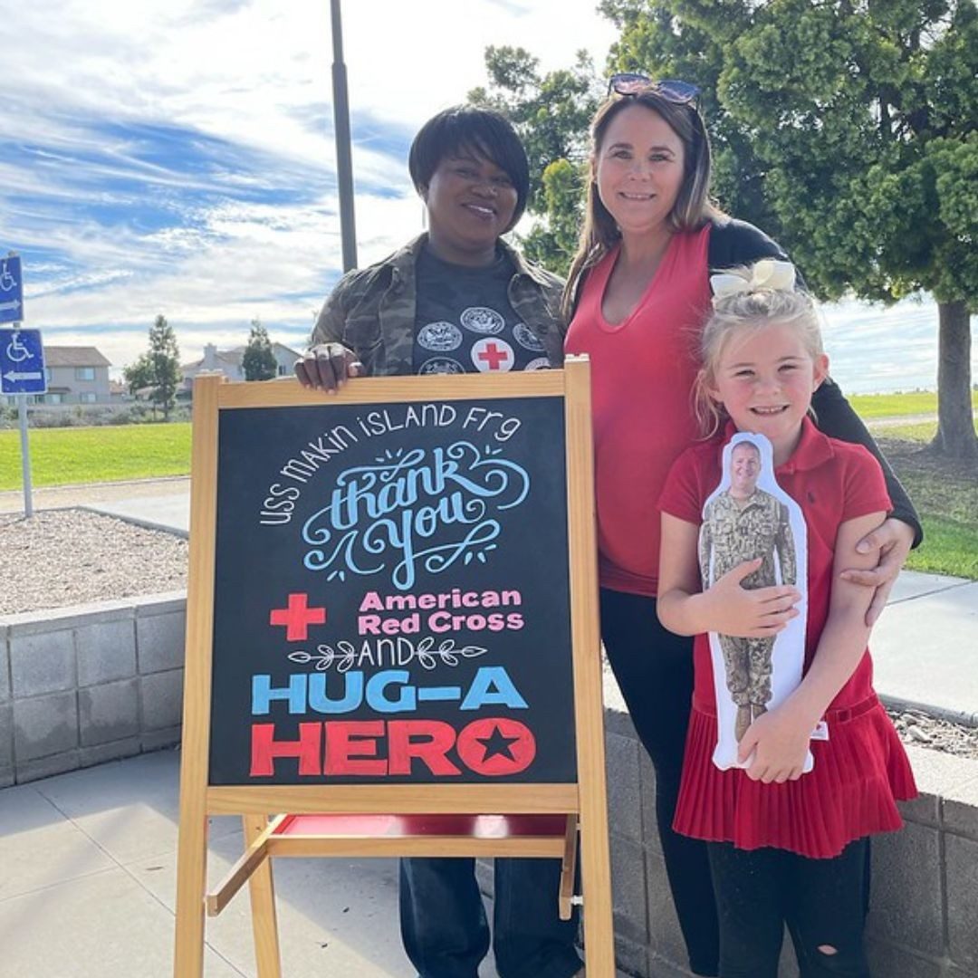 volunteers posing near hug a hero signage