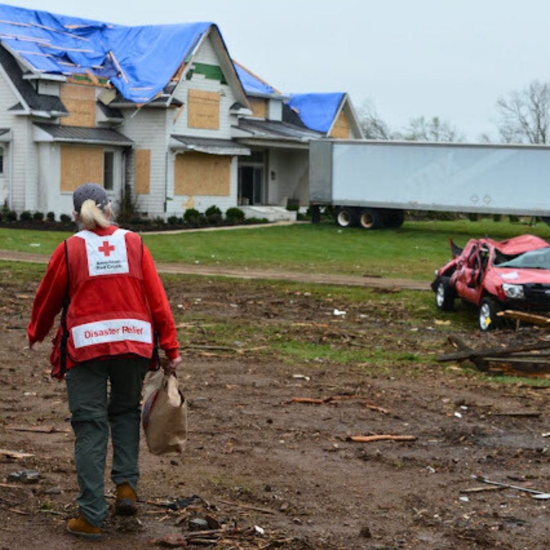 disaster responder walking towards damaged house