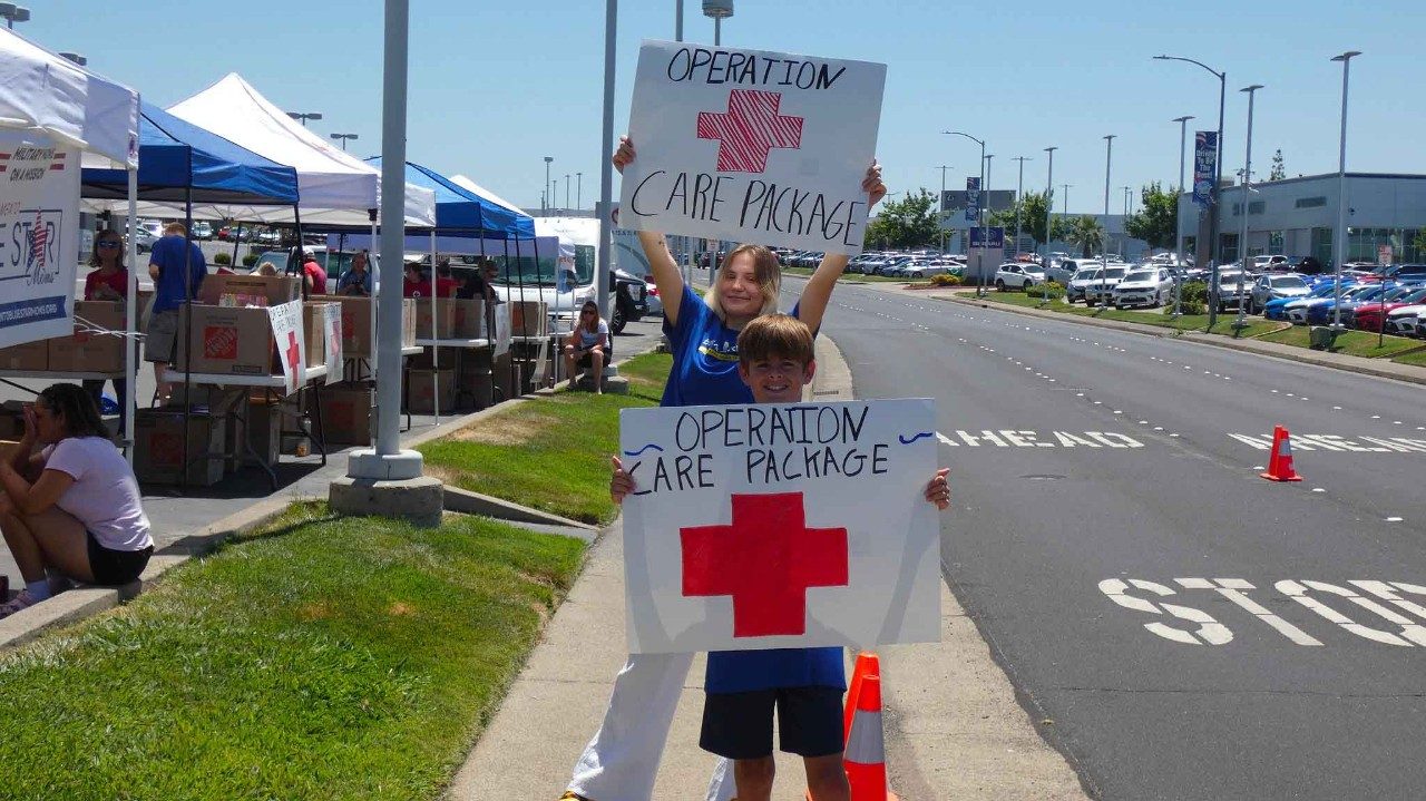 Volunteers hold signs at Operation Care Package 
