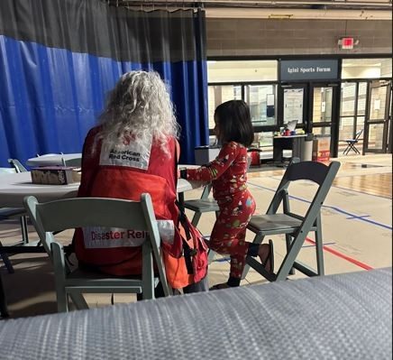 Volunteers assist a 5-year old child after her house was lost in a fire. 