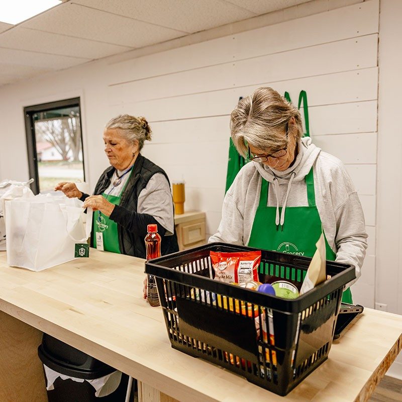 Two people filling bags and basket with packaged food.