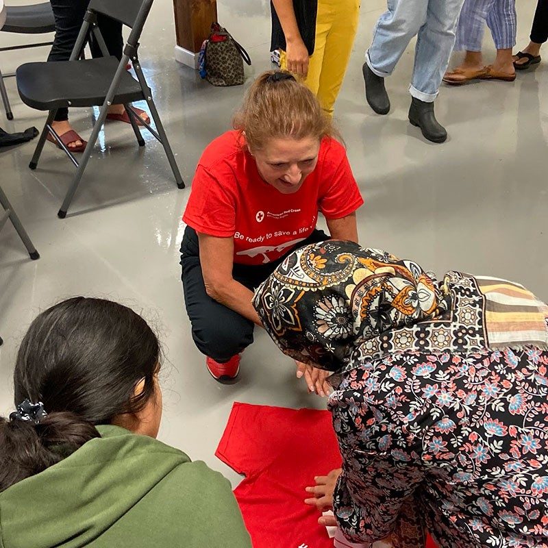 Red Cross volunteer teaching CPR to students.