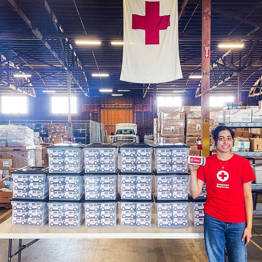volunteer stands in front of boxes of cpr training equipment