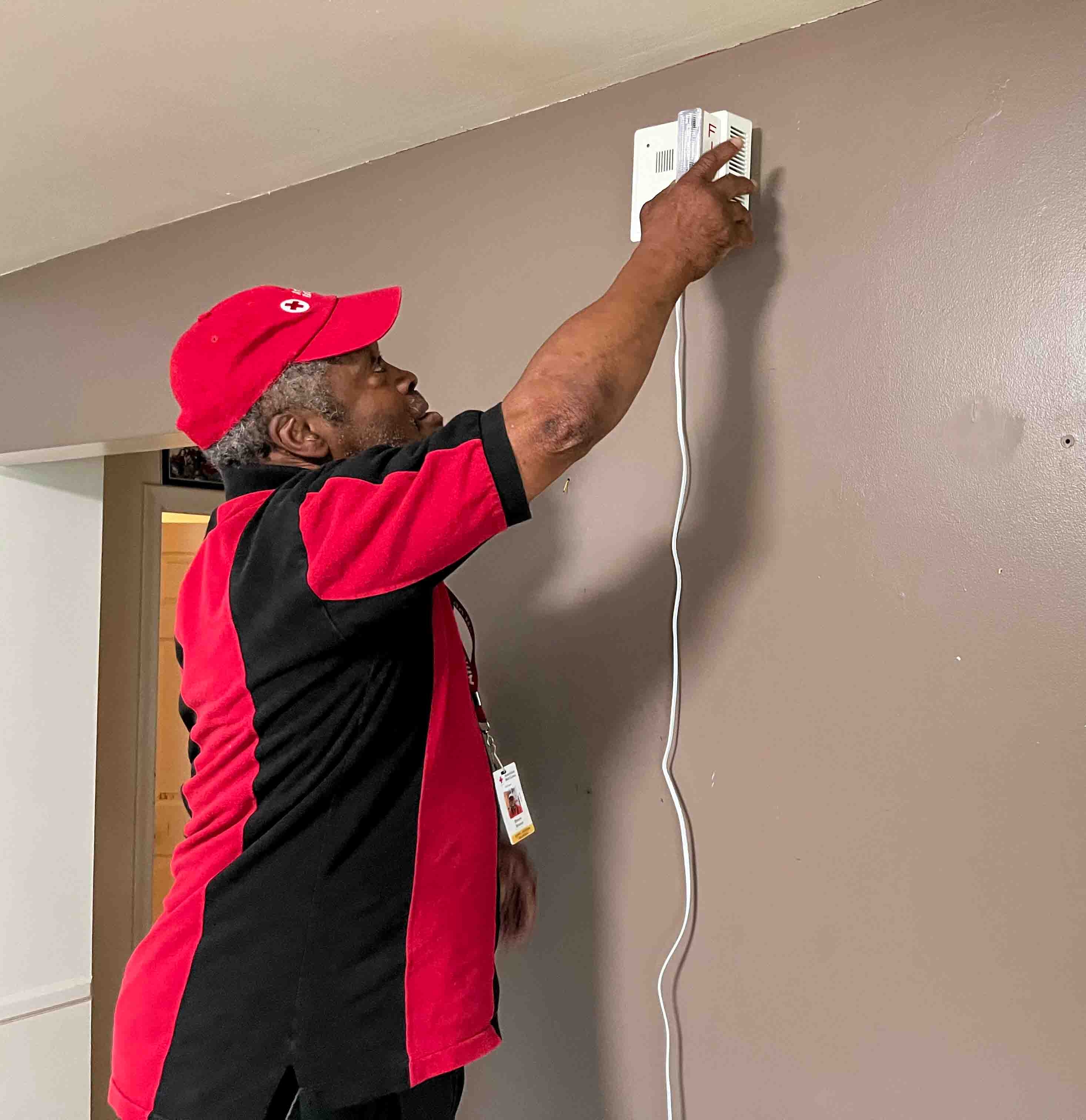 A volunteer hangs a smoke alarm