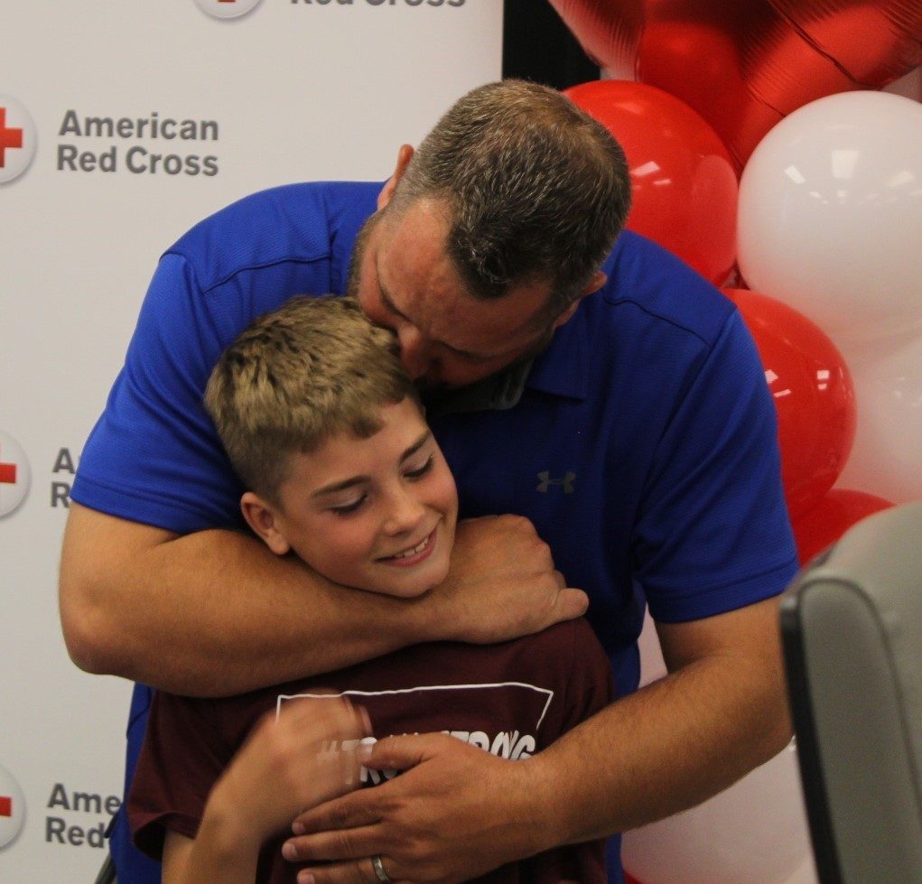 Wes Ross hugs son Troy at the Great Falls Blood Donation Center unveiling
