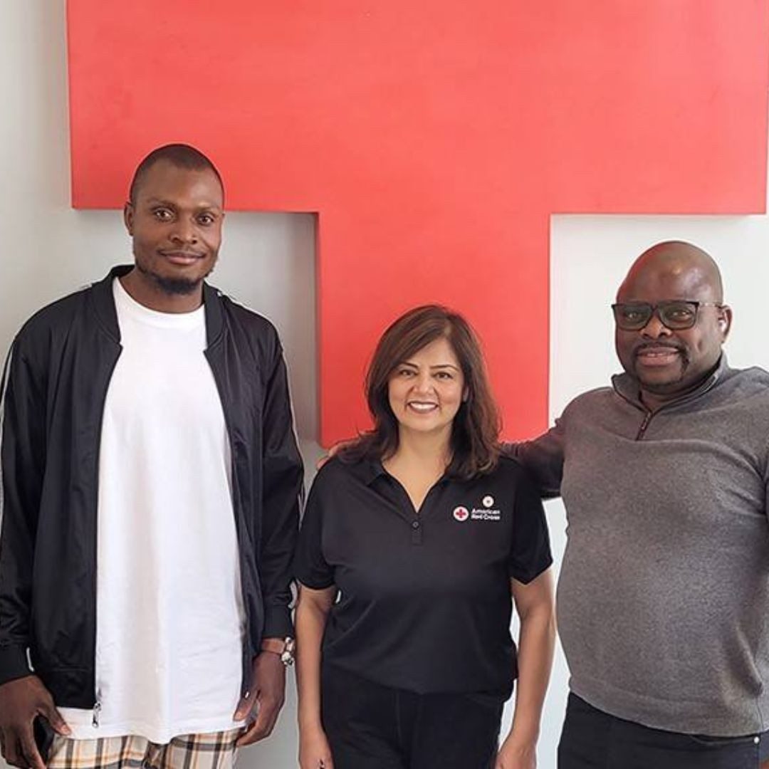 woman  and two men standing in front of red cross signage