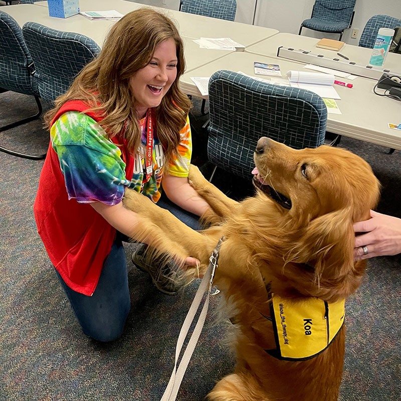 Megan Sylvester holding a Golden Retriever's paws.