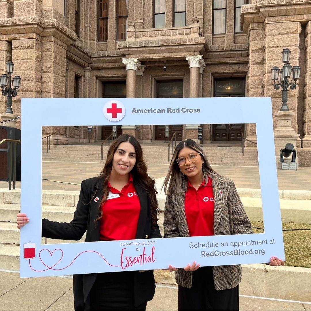redcrossers outside of state capitol posing in red cross frame