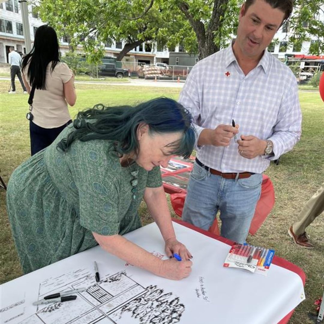 woman writing at red cross table