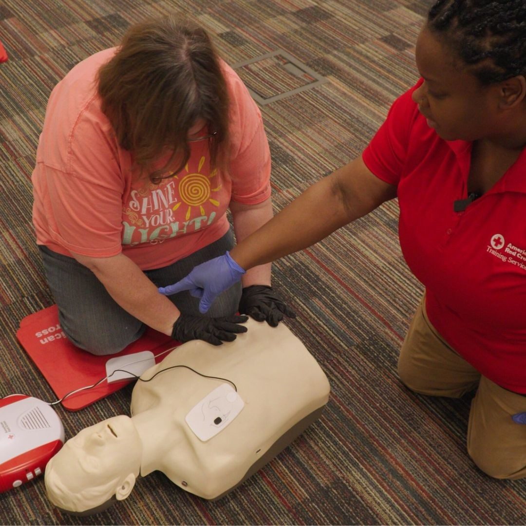 red crosser assisting woman in cpr training