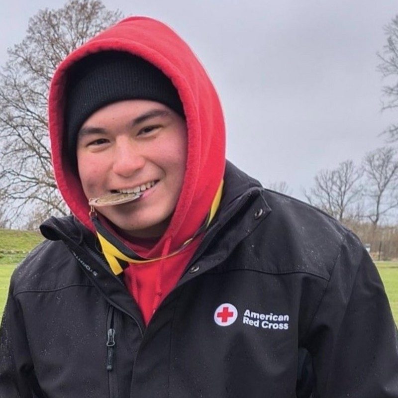 Andrew Yao in a sweater biting medal around his neck.