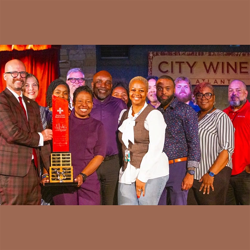 group of people on stage at an event with one of them holding a Red Cross award.