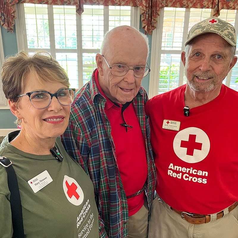 two Red Cross volunteers and a Military Veteran take a group pic.