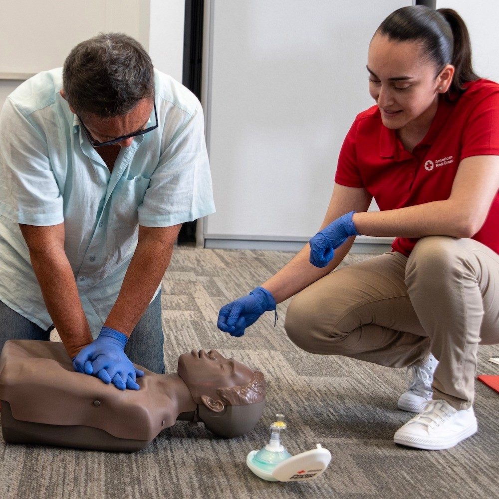 CPR training class with a student practicing on a CPR mannequin.