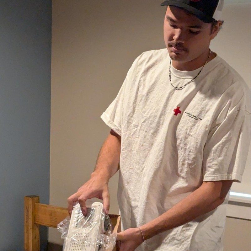 A student holding a bed-shaker alarm in hand.