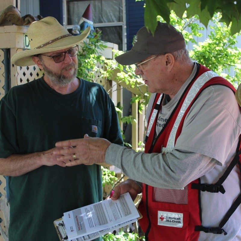  Max Nuxoll wearing a Red Cross vest talking to a client.