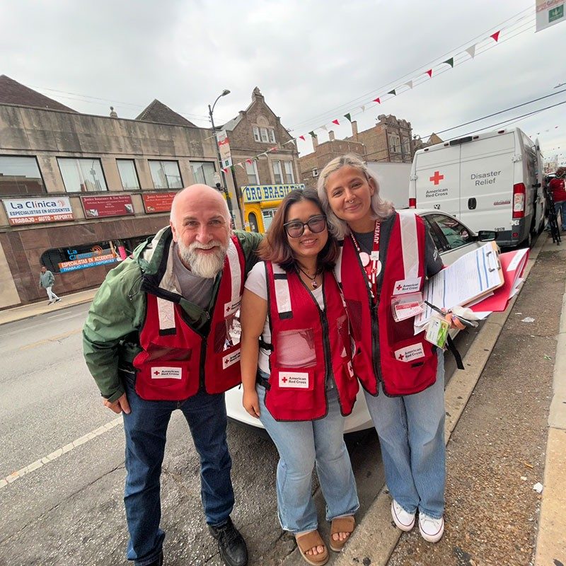 three Red Cross volunteers take a group photo while on the street.