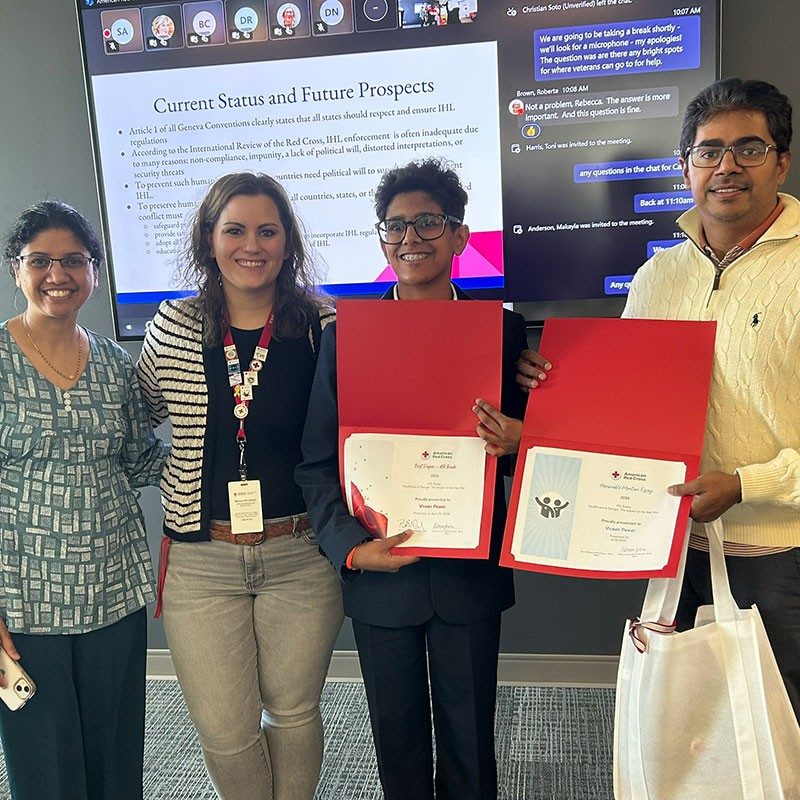 four people standing together with two of them holding awards they received at the International Humanitarian Law Symposium.