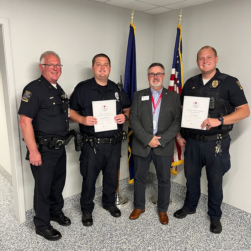 Officer Ryan Russell and Officer Eric Leap holding their American Red Cross Lifesaving Award while standing next to Mooresville Police Chief Kerry Buckner and Red Cross Executive Director Jim Griffith.