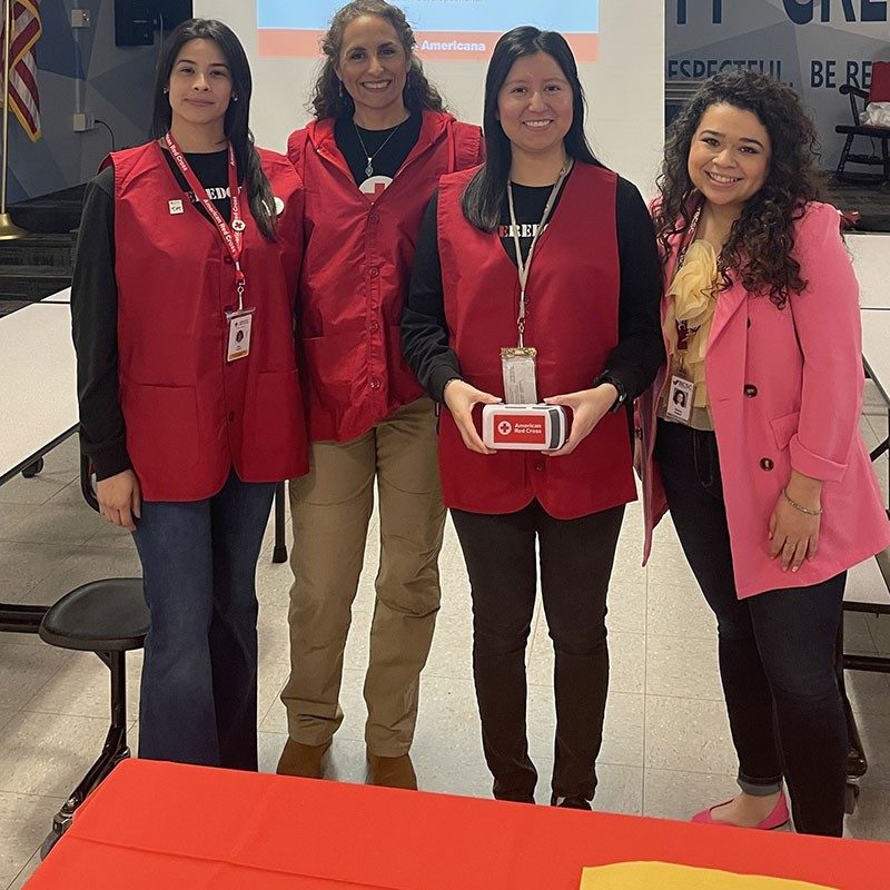 group pic of red cross volunteers with one holding a CPR Hands-Only Compression Practice tool that's in the shape of a Red Cross van.