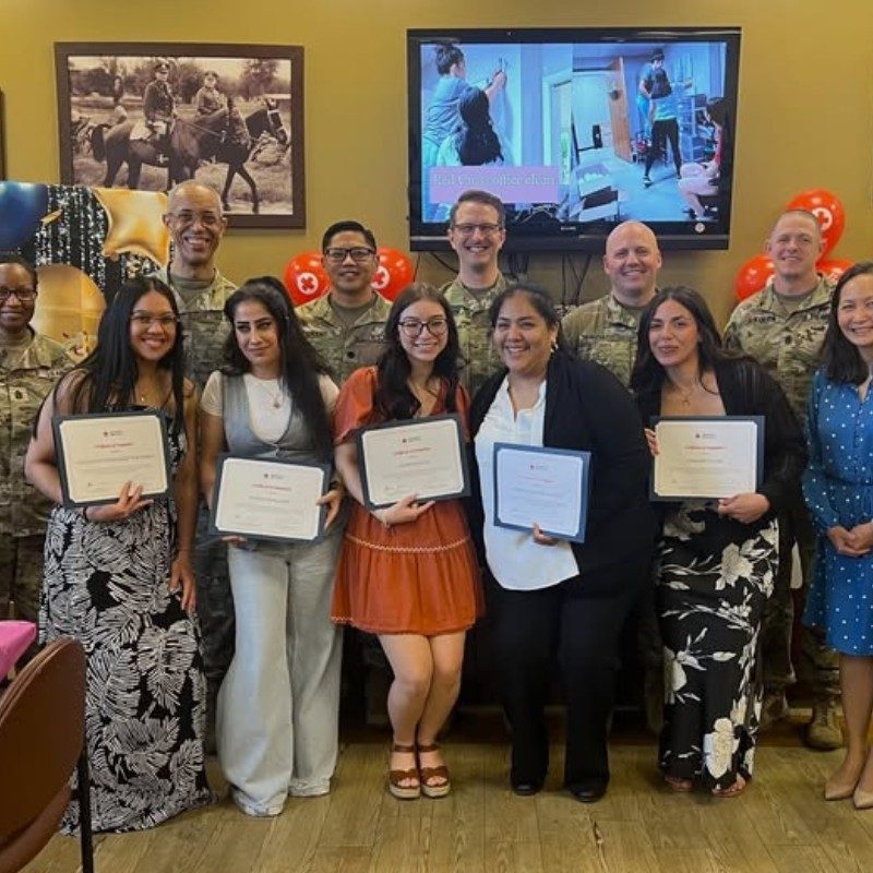 Group of service members in uniforms with their spouses holding certificates.