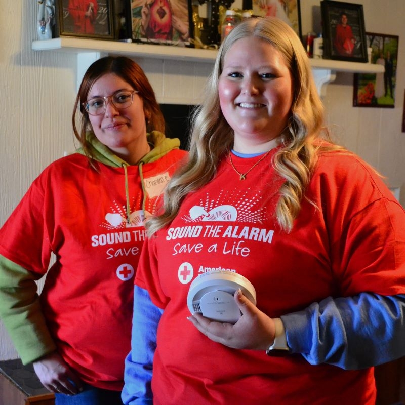 Two Red Cross volunteers holding smoke alarms.