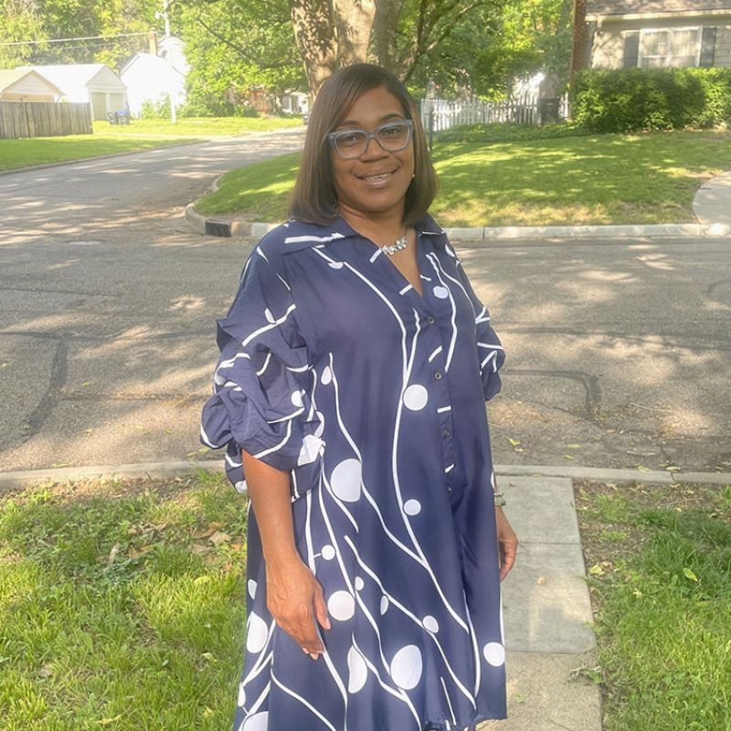 Tisharria Harris standing smiling in a blue dress.