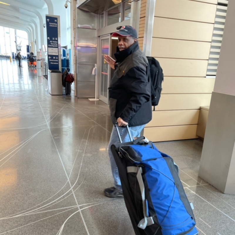 Glen Williams  carrying his suitcase through an airport.