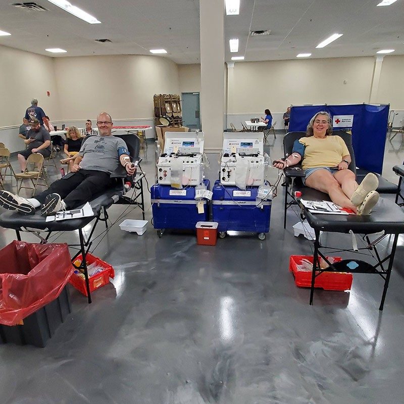 two people lying on chairs donating blood.