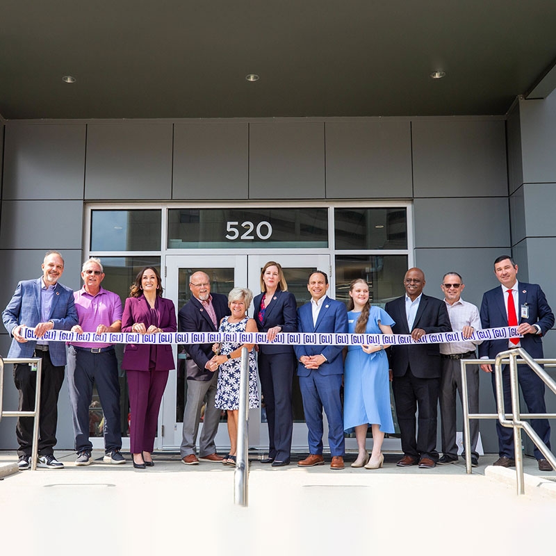 group of people about to cut the ribbon at a ribbon cutting ceremony.