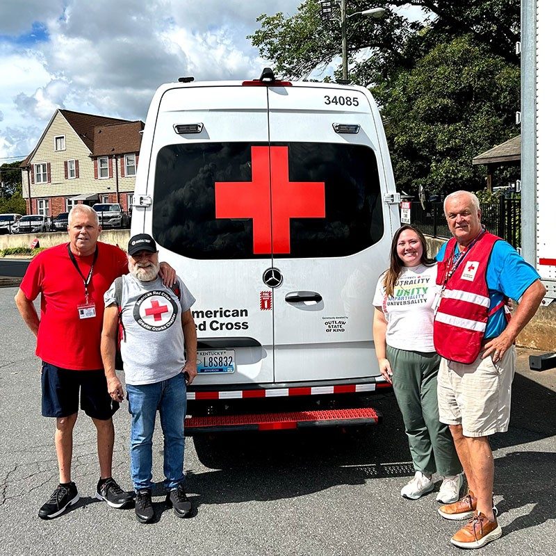 four Red Cross volunteers at the back of a Red Cross van.