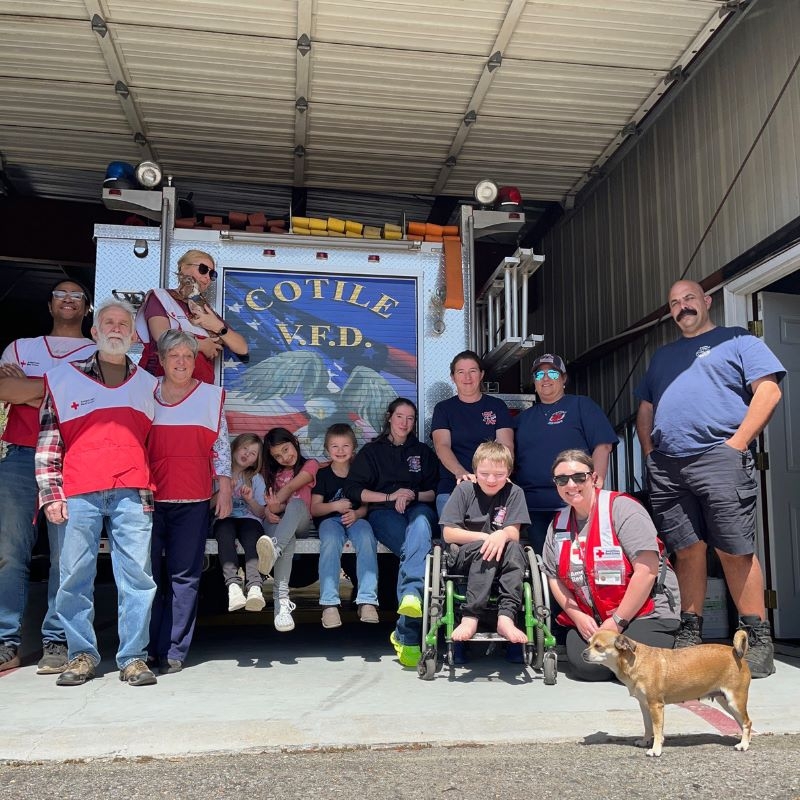 Group of people and a dog standing in front of a fire truck.