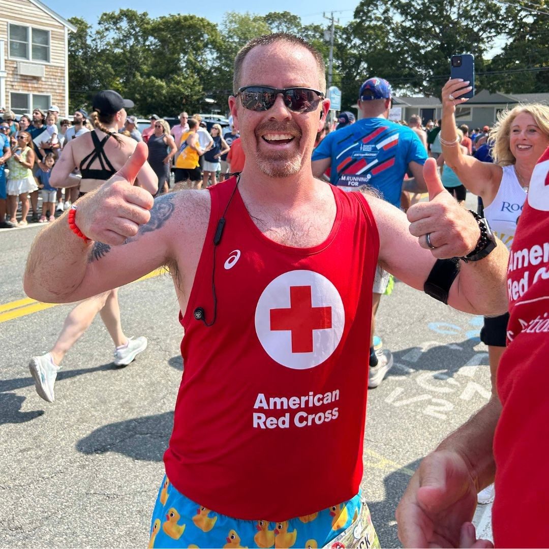 red crosser holding thumbs up while running in falmouth road race