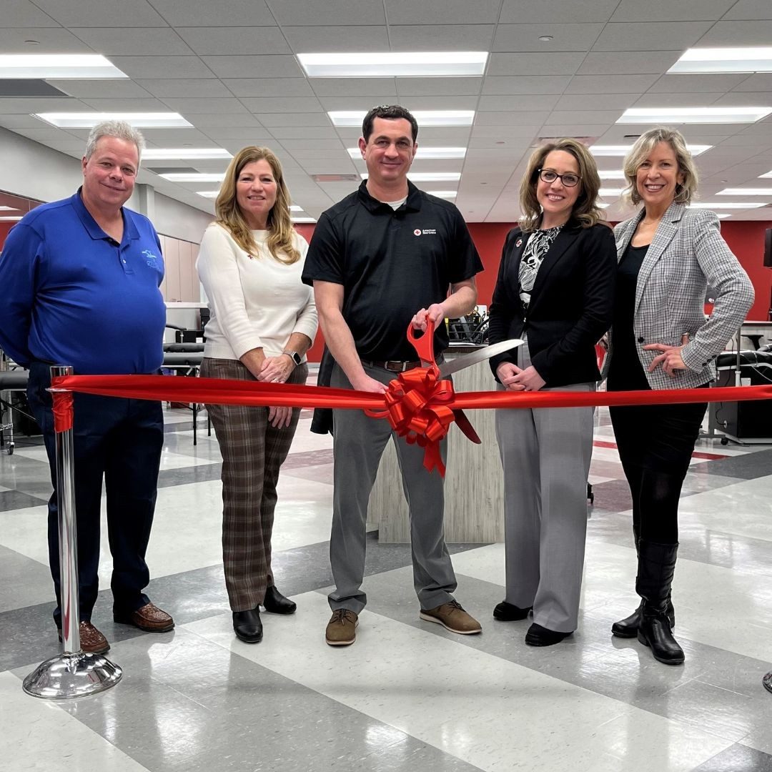 group of red crossers cutting ribbon at donation center