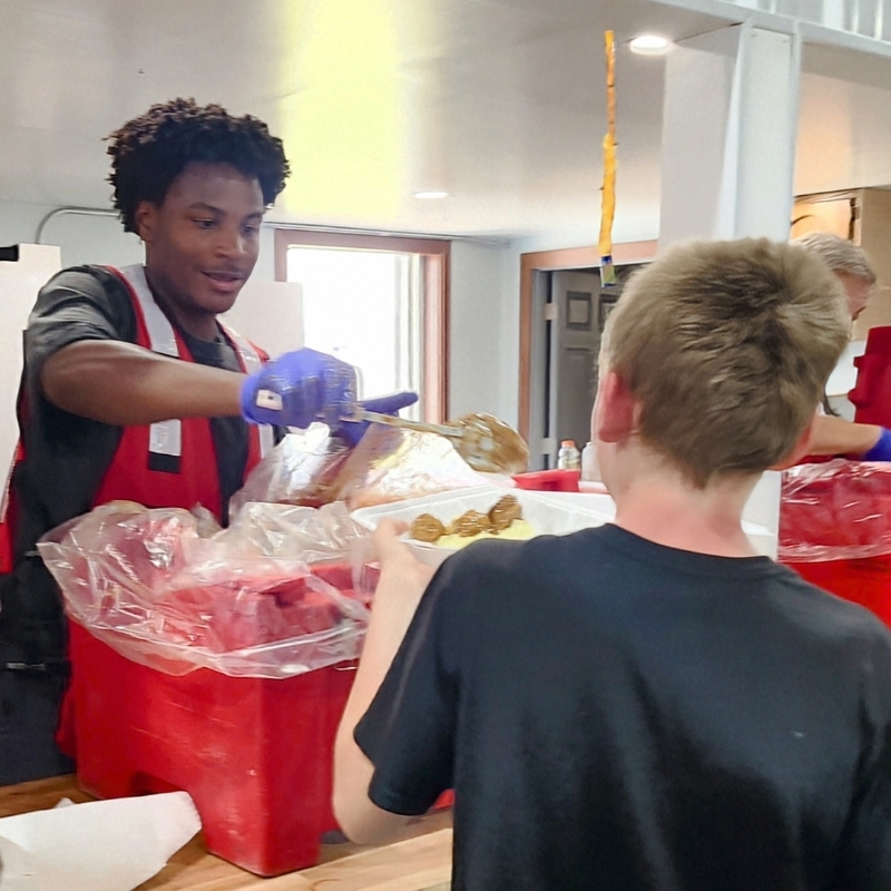Red Cross volunteer serving food to a client.