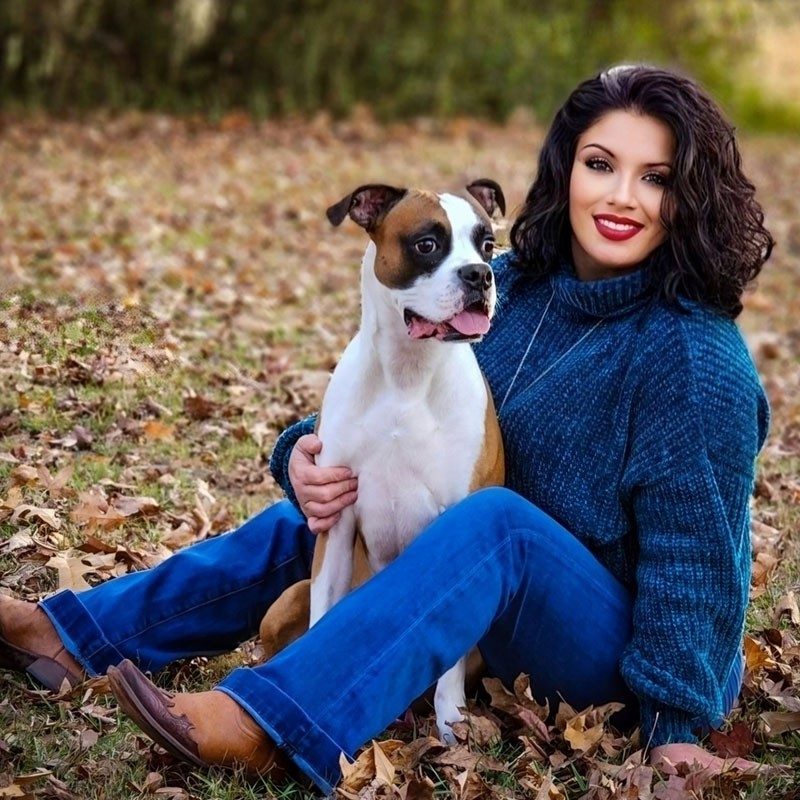 Lisa and her dog Bodie sitting in a field of autumn leaves.