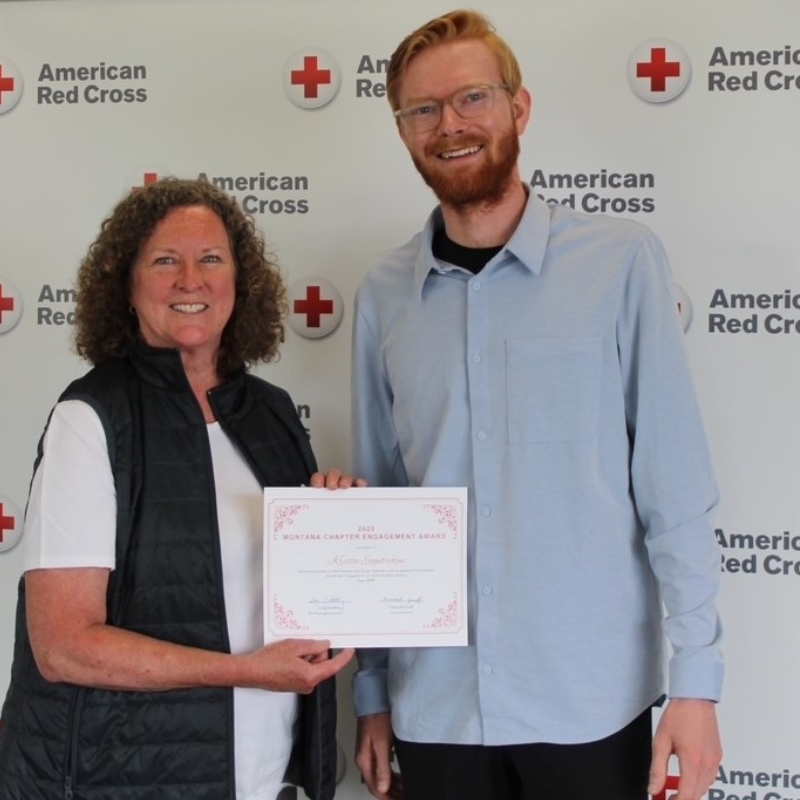 Kristie holding n award standing next to a Red Cross employee