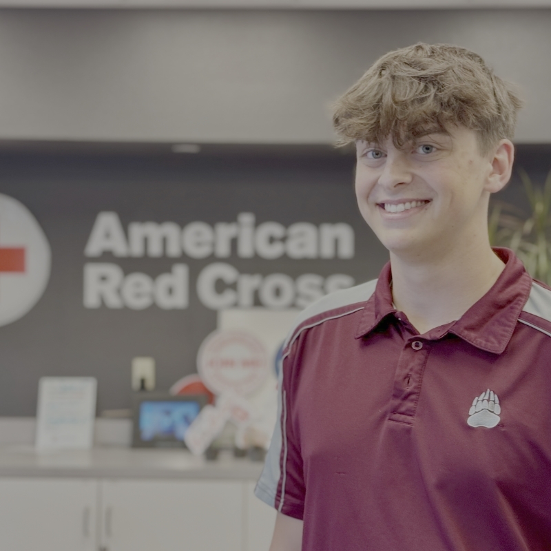 Brock Gardipee in a red shirt in front of a wall that says "American Red Cross".