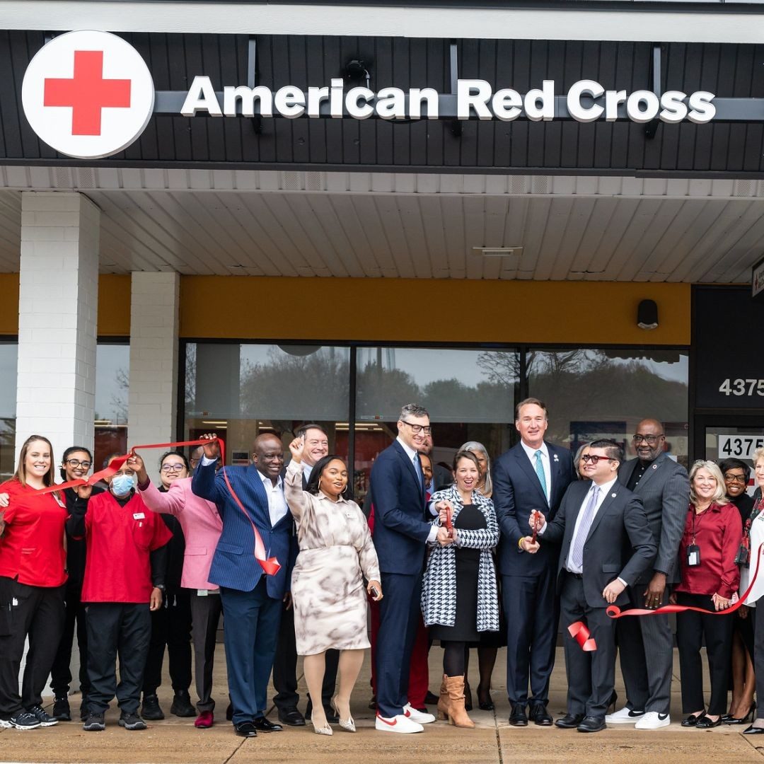 group of people and red crossers at ribbon cutting