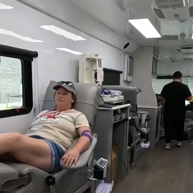 Person sitting in a chair donating blood in a blood mobile.
