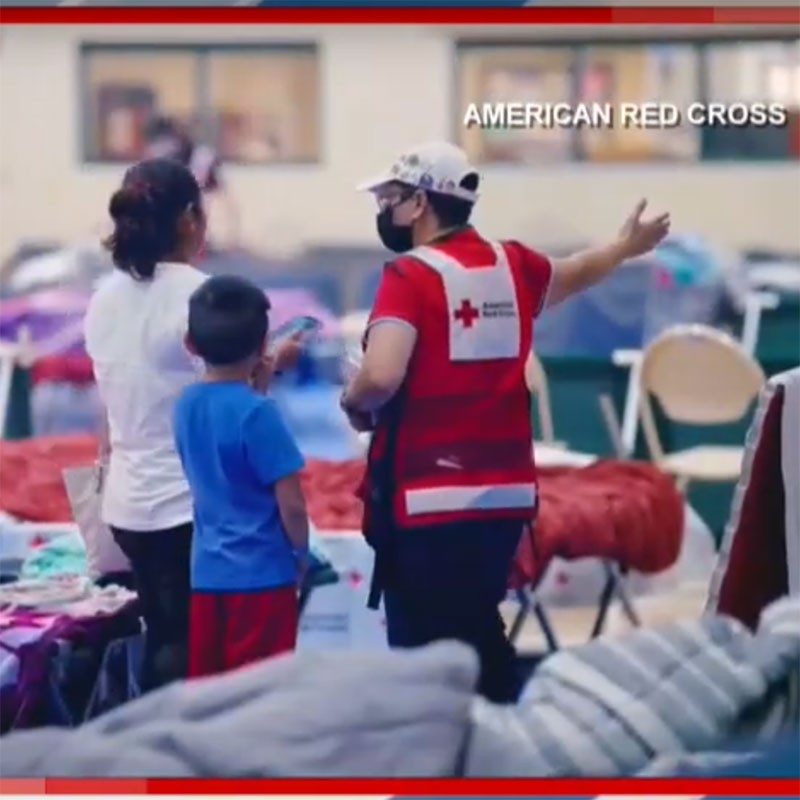 Red Cross volunteer helping a mother and child in a Red Cross shelter.
