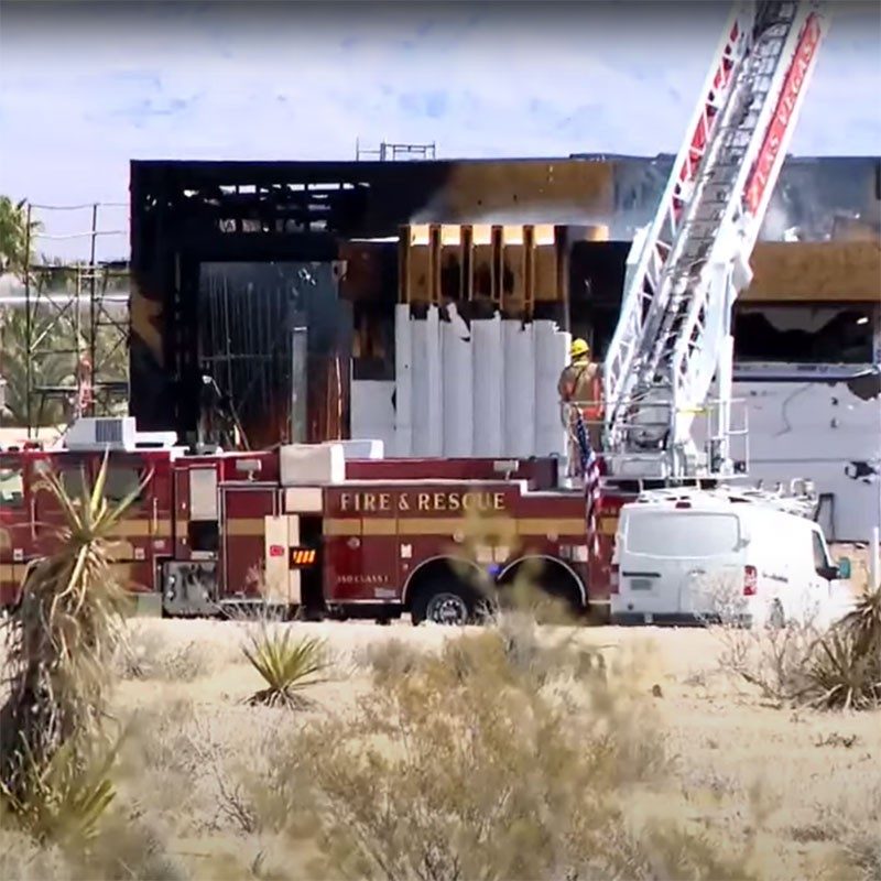fire engine with ladder extended above building that's on fire.