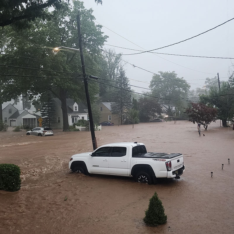 Flooded street with a pickup truck in the middle of it.