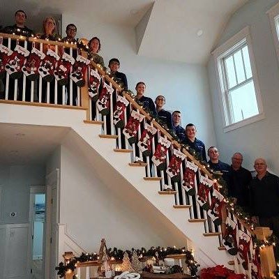 group of U.S. coast guards on a staircase with christmas stockings.